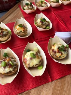 some food is sitting in small bowls on a red tablecloth with white plates and utensils