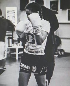 a black and white photo of a woman wearing boxing gloves