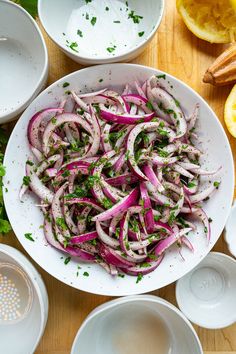 a white bowl filled with sliced onions on top of a wooden table