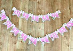 a pink and white banner that says merry christmas hanging on a wooden floor next to a pair of scissors