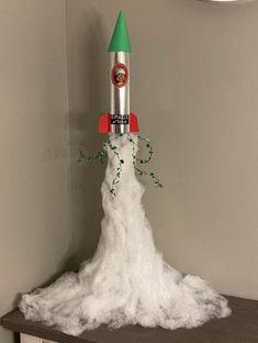 a toy rocket on top of a pile of white fluffy material in the corner of a room