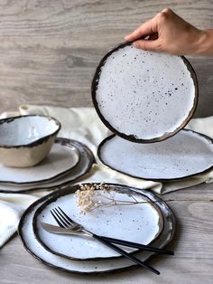 a person is holding a plate with two forks and spoons in front of it