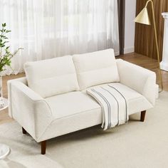 a white couch sitting in front of a window on top of a carpeted floor