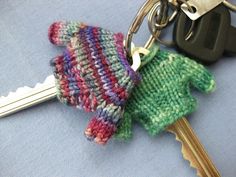 a knitted mitten keychain with two keys attached to it, sitting on top of a table