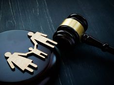 a judge's gavel and wooden cutout of two people holding hands on top of a black table