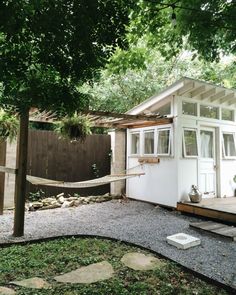 a small white house with a hammock in the yard