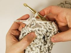 two hands crocheting the ends of a ball of yarn