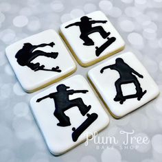 four decorated cookies with black silhouettes of skateboarders on white frosted squares