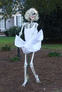 a skeleton dressed in white is holding a string and standing on the ground next to a house