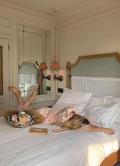 a woman laying on top of a bed next to a mirror