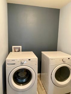 two washers and dryer in a small room with blue paint on the walls