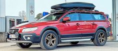 a red car with a surfboard on the roof is parked in front of a gas station