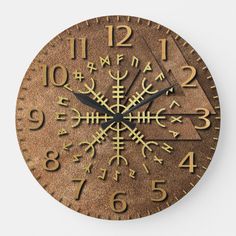 a clock that is on the wall with numbers and symbols in gold foiled metal