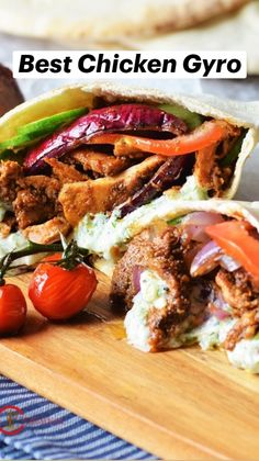 a chicken gyro is cut in half on a cutting board with tomatoes and peppers