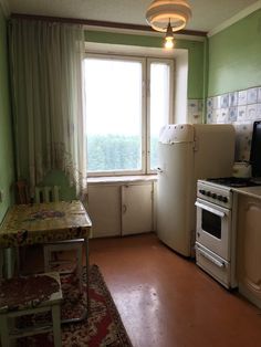 an old kitchen with green walls and white appliances in the corner, along with a small dining table