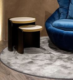 two tables sitting on top of a rug next to a blue chair