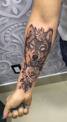 a woman's arm with a wolf and roses tattoo on the left side of her arm