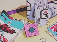 an assortment of games and magazines on a table with a can of soda in the background