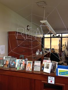 an office desk with many books and pictures on the top, along with a spider web hanging from the ceiling