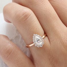 a woman's hand with a diamond ring on top of her finger and the other hand holding an engagement ring