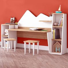 a desk with two stools and a book shelf in front of an orange wall