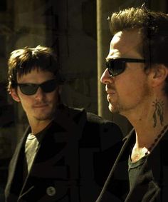 two men with tattoos on their neck and one wearing sunglasses looking at another man's face