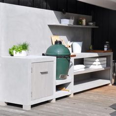 a large green egg sitting on top of a wooden table next to a white cabinet