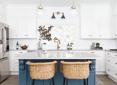 two wicker stools sit at the center of a kitchen island in front of a stainless steel refrigerator