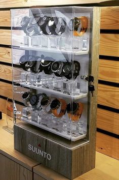 a display case filled with lots of watches on top of a wooden table next to a wall