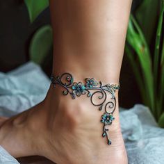 a woman's foot with a blue flower ankle bracelet on top of her leg