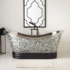 a bath tub sitting on top of a white floor next to a mirror and potted plant