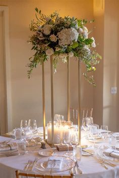 an elegant centerpiece with white flowers and greenery