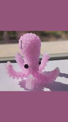 an octopus made out of beads sitting on top of a window sill in front of a window