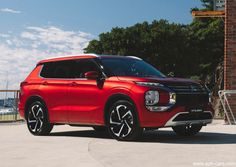 a red suv parked in front of a brick building with trees and water in the background