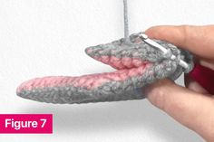 someone is crocheting an object that looks like a snake's mouth with pink and gray yarn