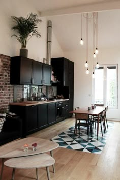 a living room filled with furniture next to a kitchen and dining room table in front of a brick wall