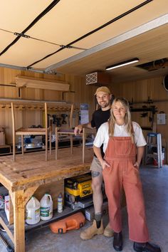 two people standing in front of a workbench with tools on the table and one person wearing overalls