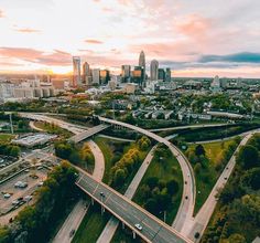 an aerial view of a city with freeways and roads in the foreground at sunset