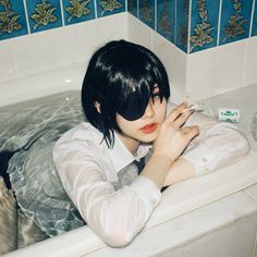 a woman with black hair sitting in a bathtub