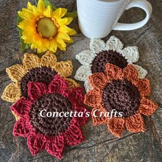 three crocheted flower coasters next to a coffee cup and sunflower on a table