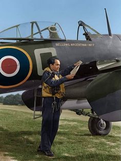 a man standing in front of an airplane reading a piece of paper on the ground