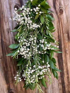 a bunch of white flowers and green leaves on a wooden surface with planks in the background