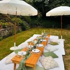 an outdoor table set up with white umbrellas