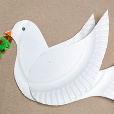 a paper plate shaped like a bird with a green pom - pom in its beak