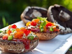 three mushrooms with different toppings sitting on a white plate outside in the sun,