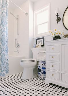 a white toilet sitting in a bathroom next to a sink and shower stall with blue and white decor on the walls