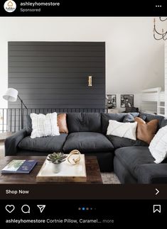 a living room with black couches and white pillows on the sofa, along with a coffee table