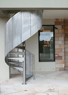 a metal stair case in front of a brick wall and glass door on the second floor