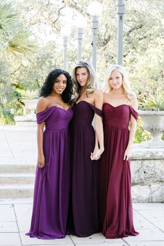 three women in long dresses standing next to each other