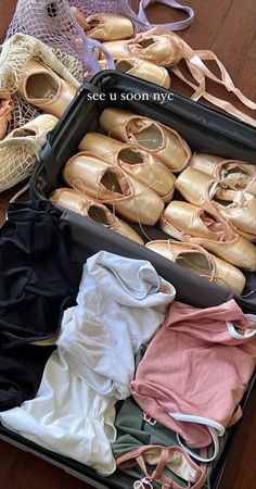 an open suitcase filled with lots of different types of shoes and clothing on top of a wooden floor